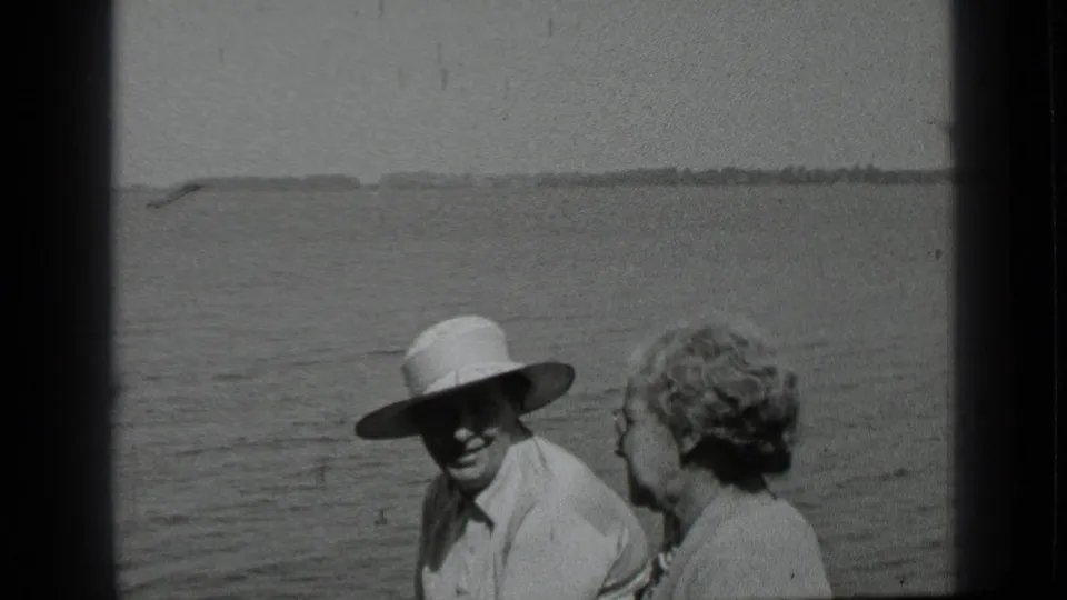 At Clear Lake in 1939, a man in a broad hat sits near a woman on a boat with open water and shoreline in the background.