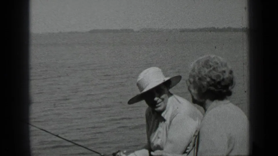 The man in a hat looks toward the woman as a fishing rod extends across the Clear Lake boat scene.