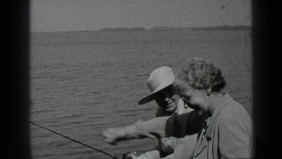 During the 1939 Clear Lake outing, the woman smiles and gestures forward while the man sits nearby with fishing gear visible.