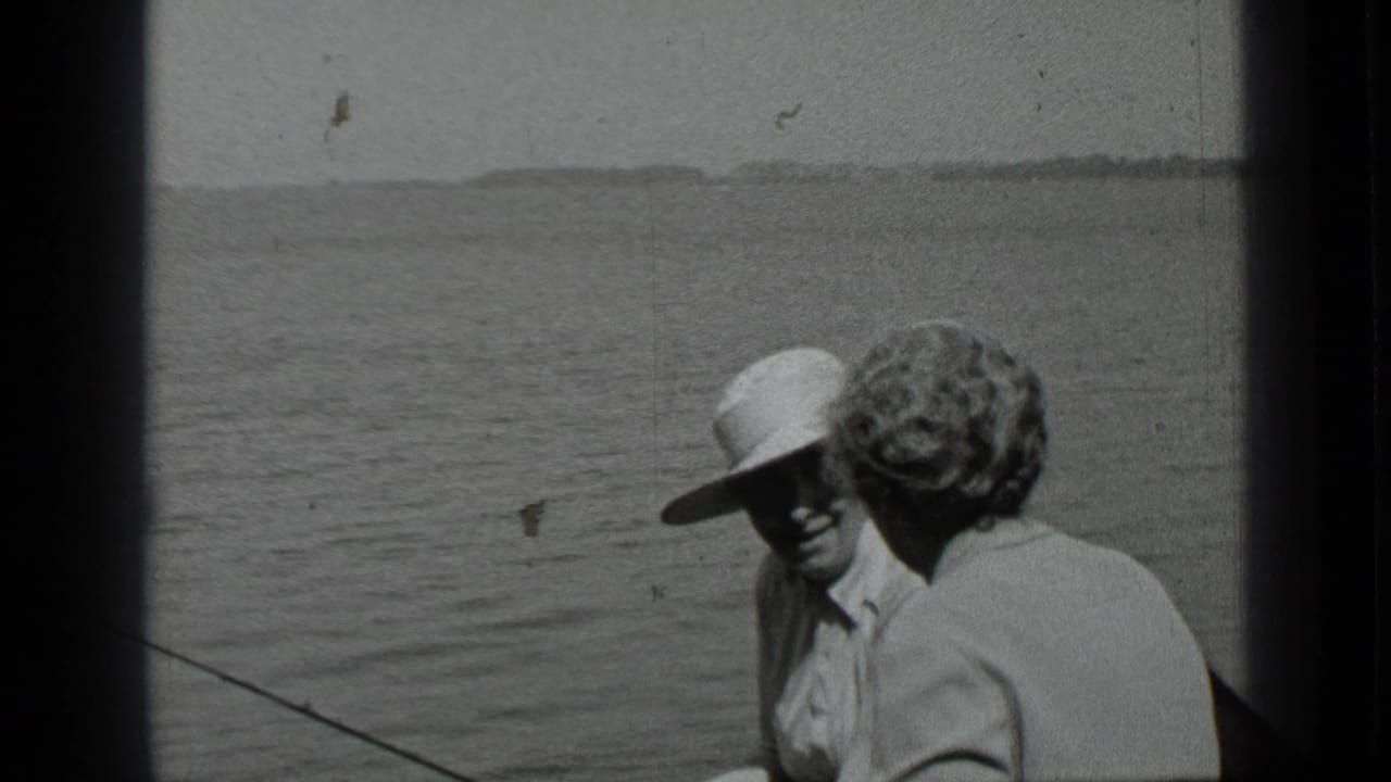 The woman faces the man in the wide-brimmed hat on a boat at Clear Lake, with open water and a low shoreline beyond.