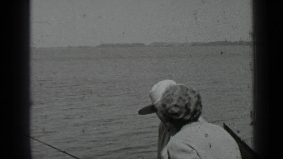 Two adults in a small boat face the lake at Clear Lake, California, in a black-and-white 1939 home-movie frame.