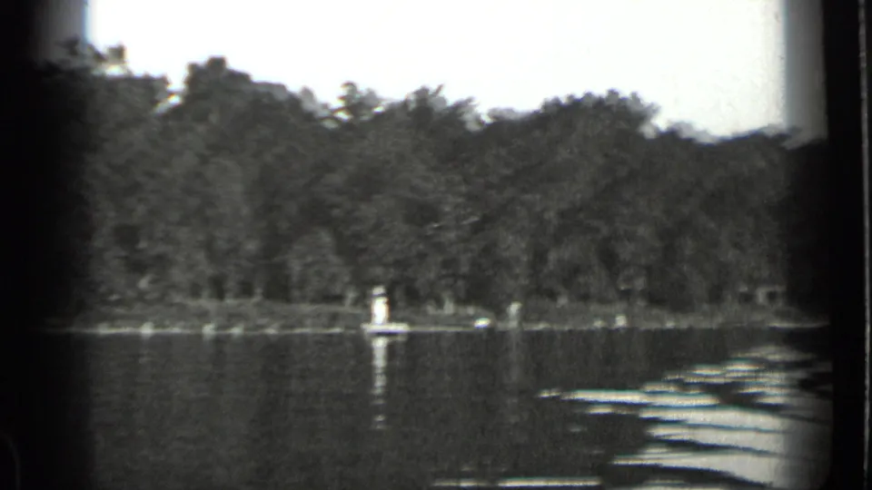 1939 Clear Lake, California view across rippling water toward a dense treeline and small distant figures near shore.