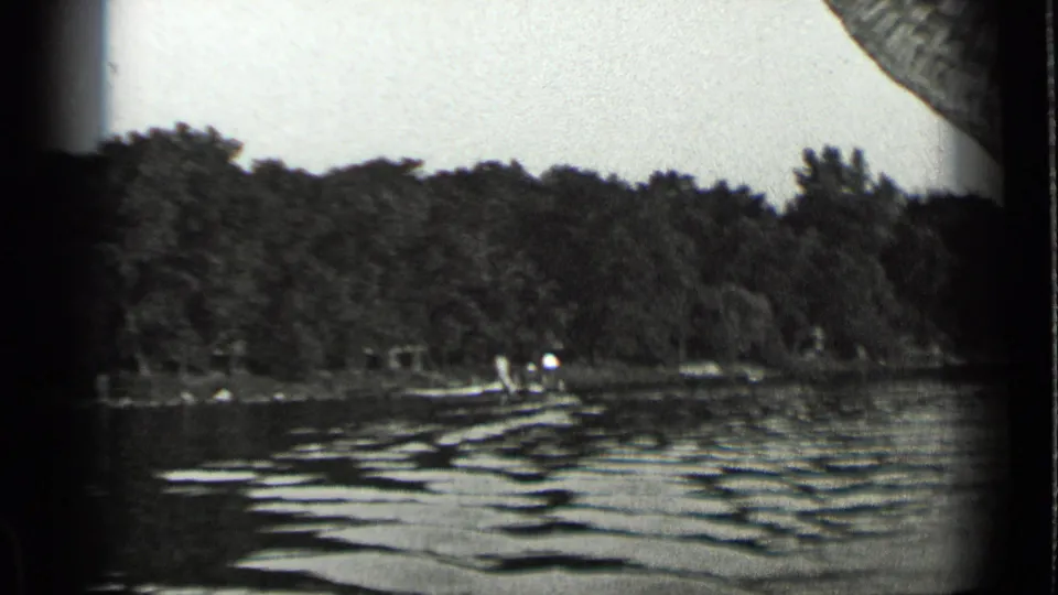 Clear Lake shoreline in 1939 with textured water, a small boat near shore, and distant people against trees.