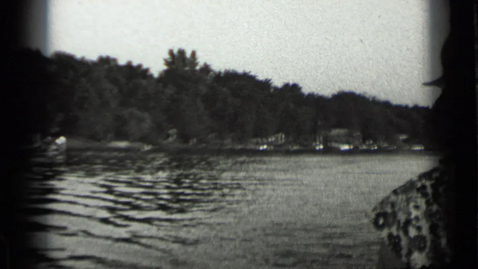 Wide 1939 Clear Lake view showing rippled water, wooded banks, small boats, and distant activity along the shore.