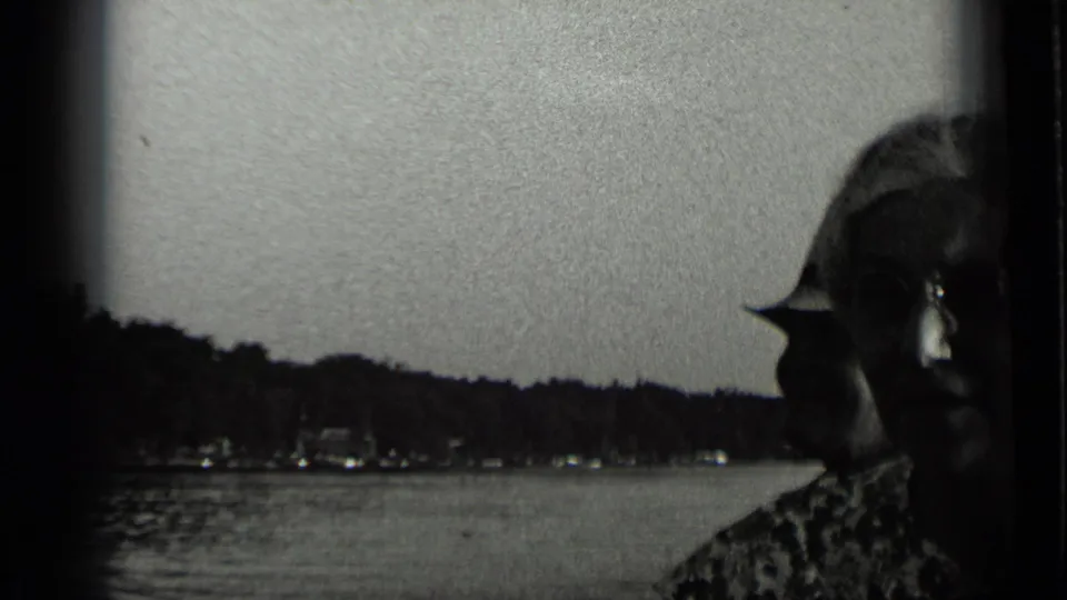 In 1939 Clear Lake, California home-movie footage, a woman in patterned clothing appears near the camera with water and wooded shoreline behind her.