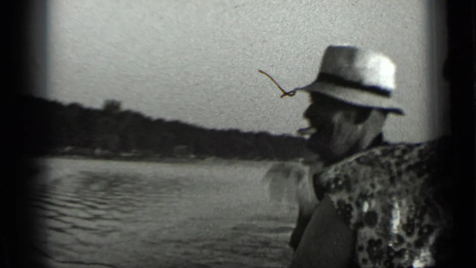 The man is shown in profile wearing a light hat near Clear Lake, with open water, shoreline, and film-edge vignetting visible.