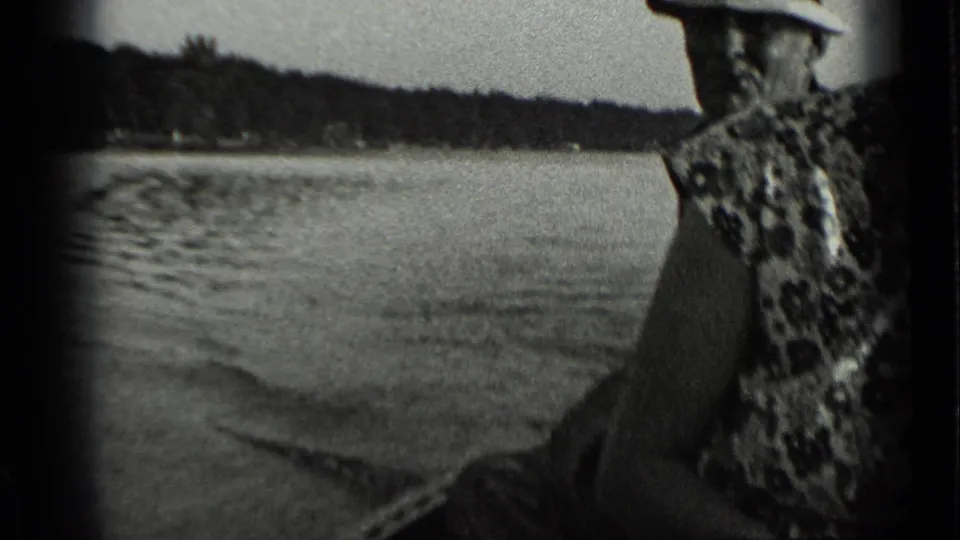 1939 Clear Lake home-movie frame with a partial view of a woman in patterned clothing as the boat travels across open water.