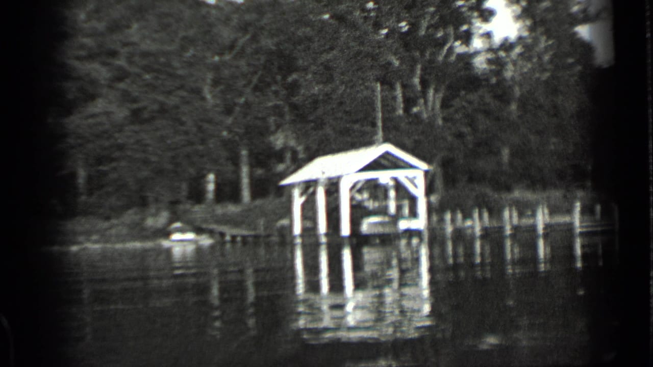 Clear Lake, California frame with a covered dock structure, small boat near shore, dense trees, and reflected light on the lake.