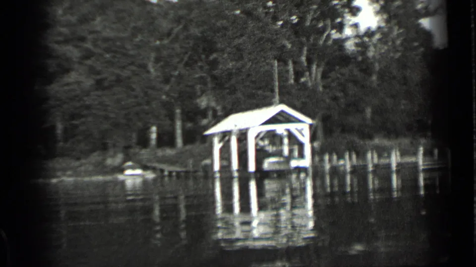 Clear Lake, California frame with a covered dock structure, small boat near shore, dense trees, and reflected light on the lake.