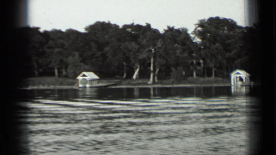 Clear Lake, California, 1939 home-movie frame showing rippled water, trees, and small white shore structures from a boat.