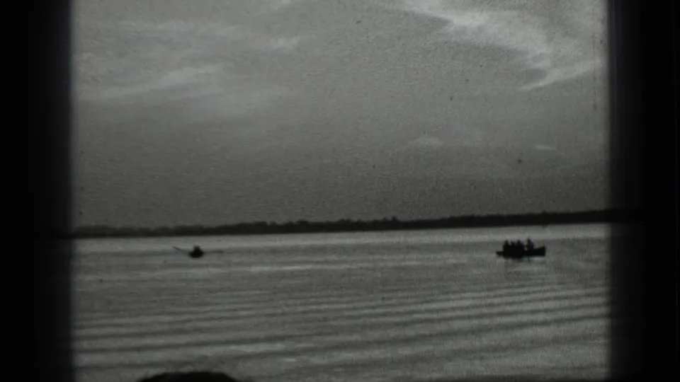 Distant rowboat with occupants crossing Clear Lake in 1939, seen under a broad sky and near a low shoreline.