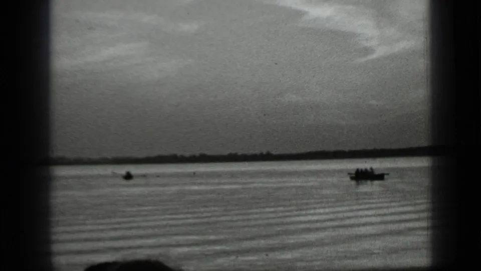 1939 Clear Lake home-movie frame showing silhouetted small boats on rippled water below a low distant shore.