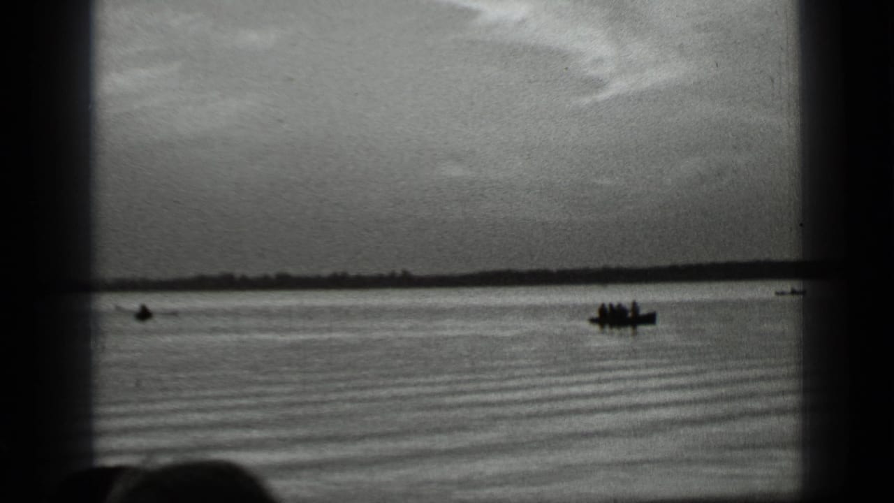 Clear Lake, California footage shows distant people in small boats silhouetted against the water and horizon.