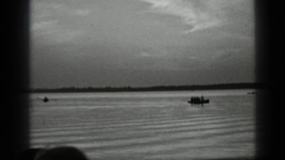 Clear Lake, California footage shows distant people in small boats silhouetted against the water and horizon.