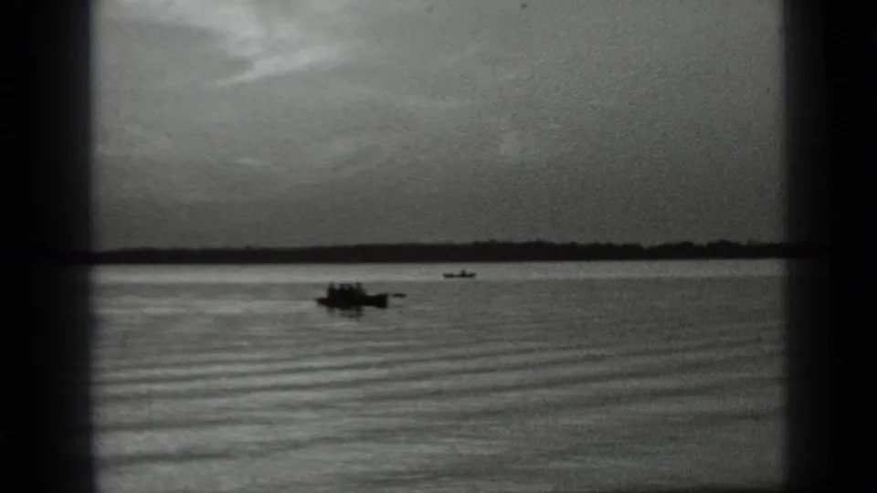 Wide 1939 Clear Lake view with a small boat far from camera, calm water, soft horizon, and black 8mm frame edges.