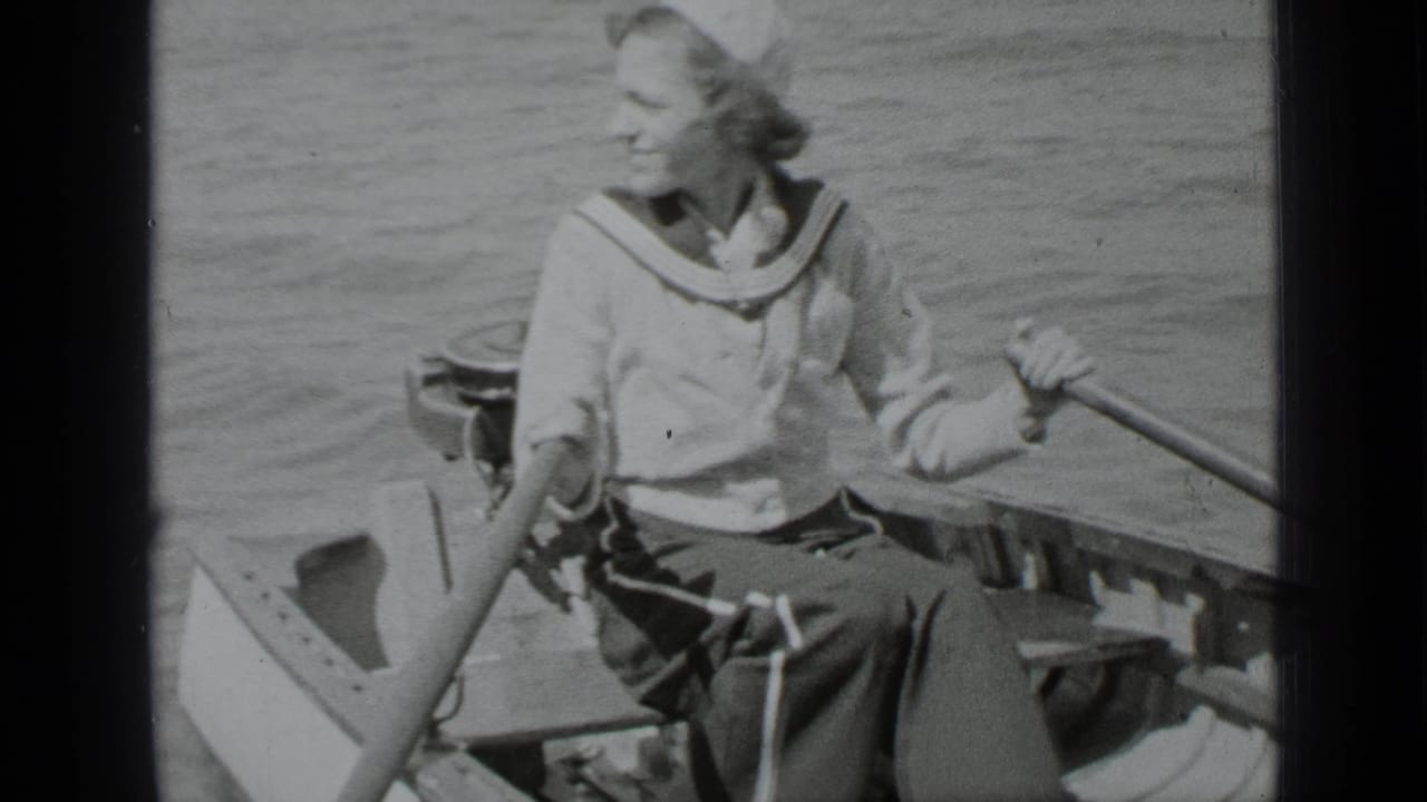 Smiling woman in a rowboat turns while holding an oar.