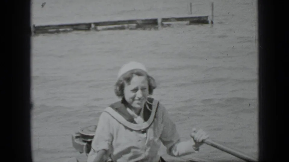 A woman sits in a small rowboat on Clear Lake, with rippled water and a distant dock visible behind her.
