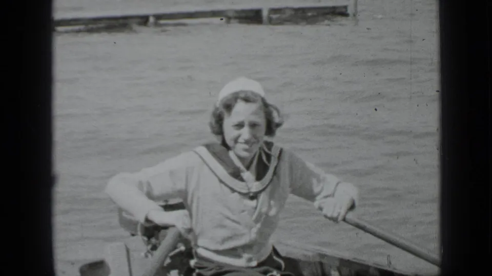 A young rower in sailor-style clothing sits in a canoe on Clear Lake, California, in 1939 home-movie footage.