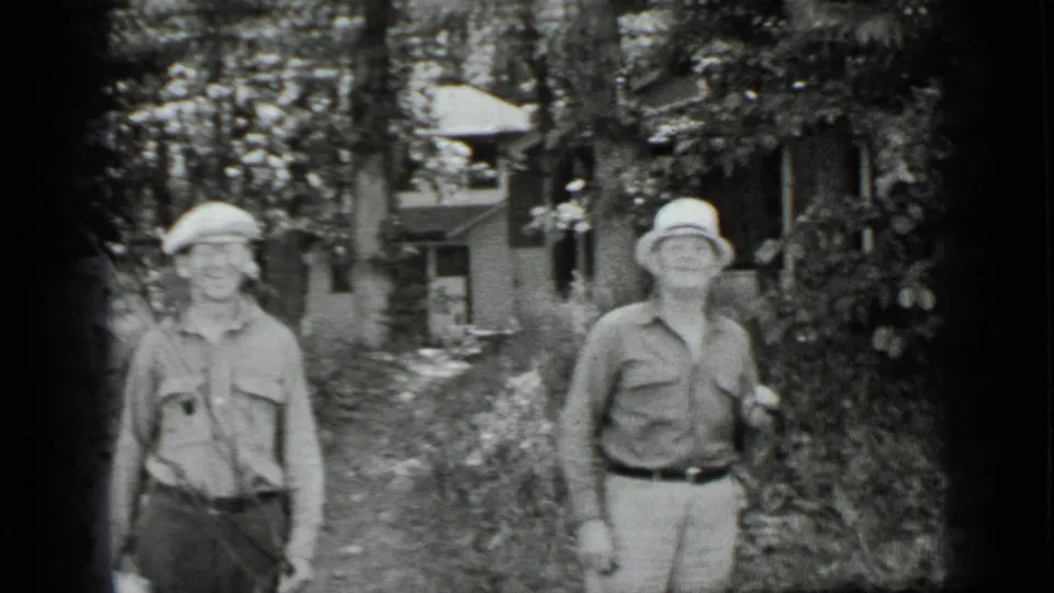 Two men in casual 1939 vacation clothing face the camera near trees and a cabin at Clear Lake, California.