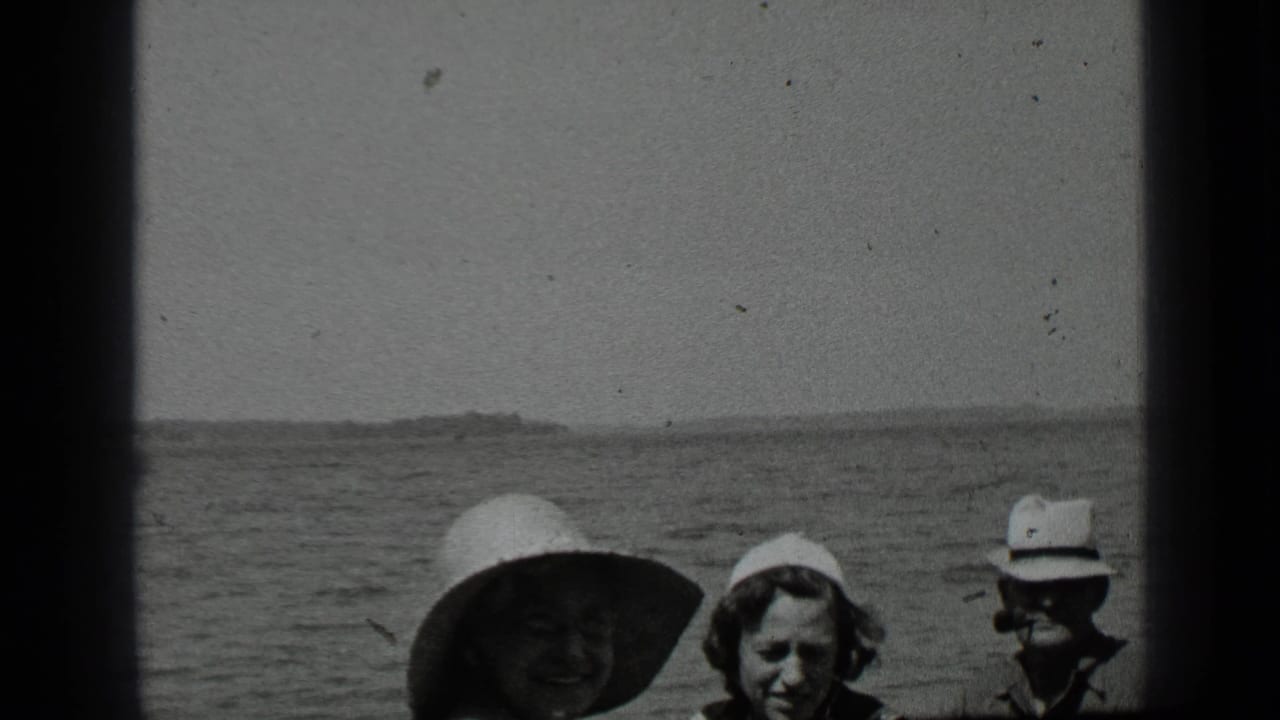 Three people in hats near a lake, partly cropped by the film frame.