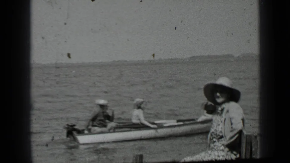 At Clear Lake, California, a woman in a wide-brimmed hat sits near a dock while people in a small boat wait on the water.
