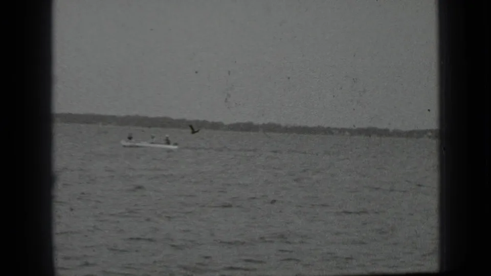 Clear Lake motorboat scene from 1939 home-movie footage, with people visible in the boat and shoreline behind.