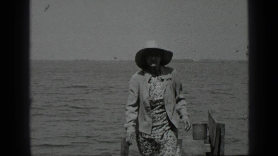1939 Clear Lake home-movie frame showing a woman in a wide-brimmed hat near the shoreline with open water behind her.