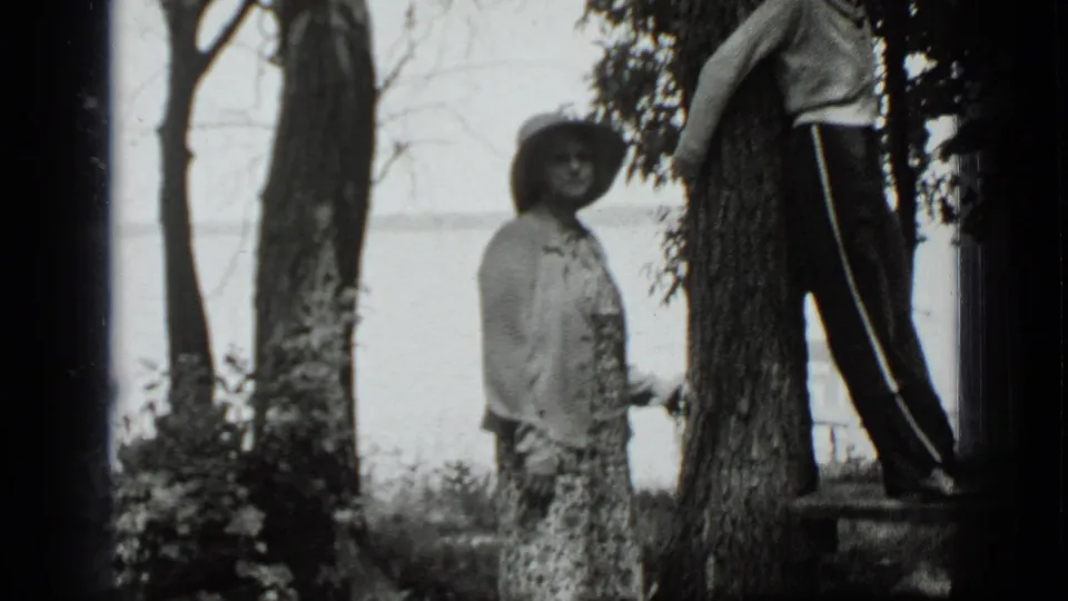 In Clear Lake, California in 1939, two adult women pose in a wooded lakeside yard, with water visible through the trees.