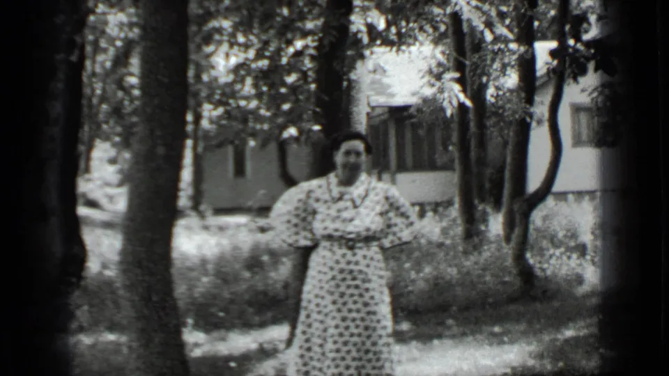 In 1939 Clear Lake home-movie footage, a woman in a polka-dot dress stands in a wooded area with a house behind her.