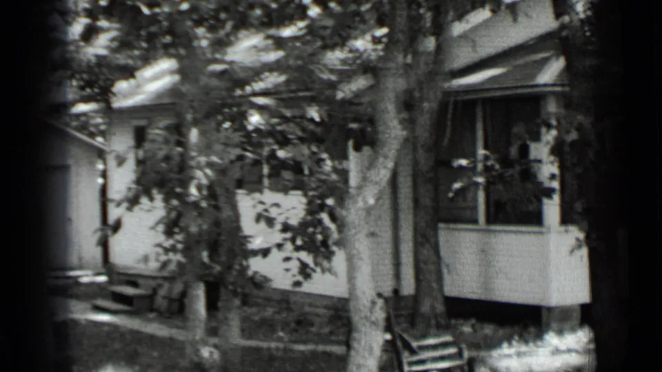 1939 Clear Lake frame with the side of a white house, porch windows, front steps, and mature trees.