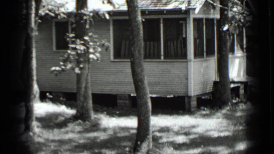 A closer Clear Lake frame shows the wooden house exterior, porch corner, trees, and shaded lawn.