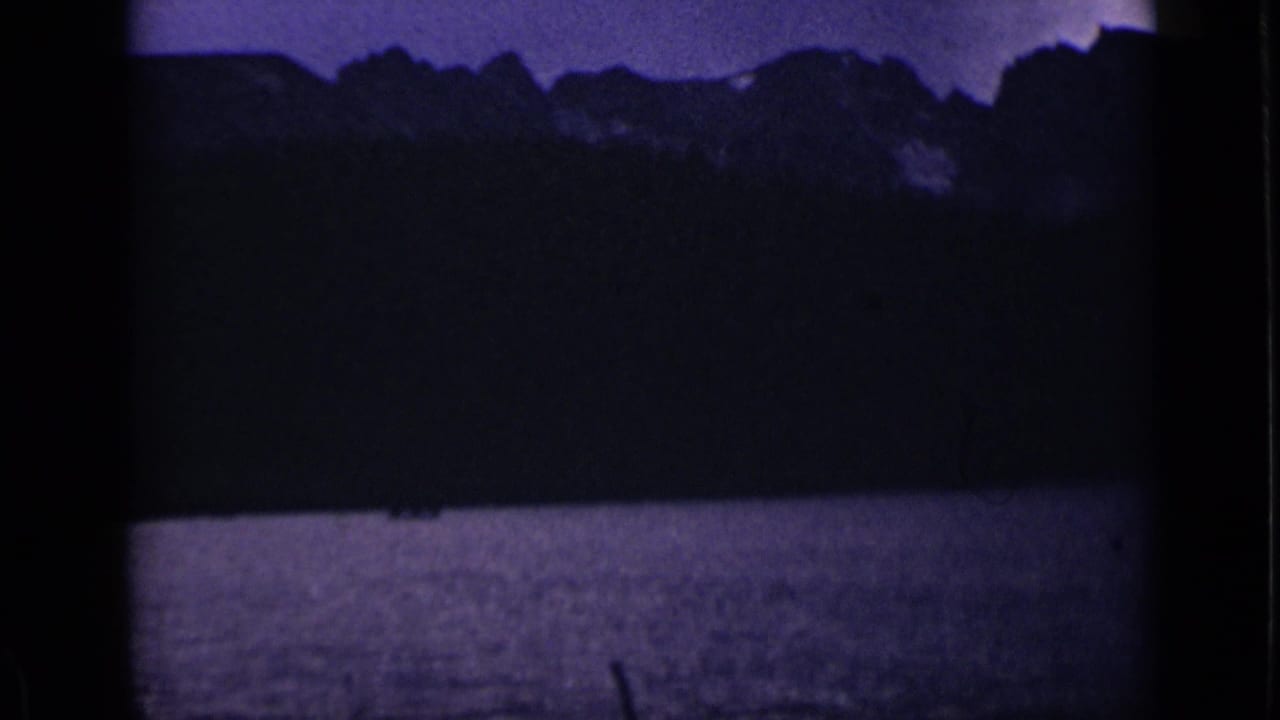 Dark mountain ridge above a lake under a purple dusk sky.