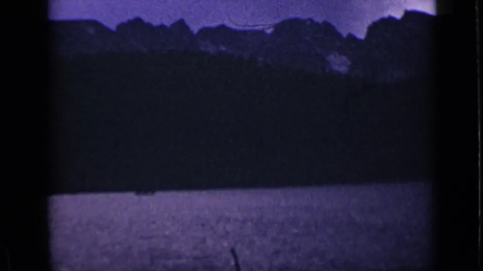 1939 Colorado landscape frame with a dark ridge line, lake foreground, purple sky, and strong 8mm edge shadows.