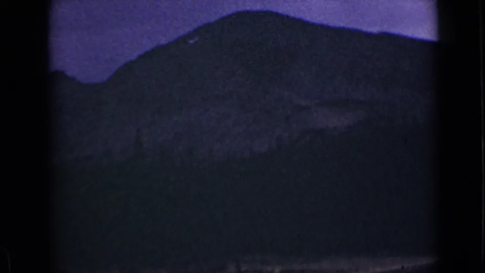 1939 Colorado home-movie frame with a dim mountain lake view, dark ridge line, and visible 8mm frame edges.