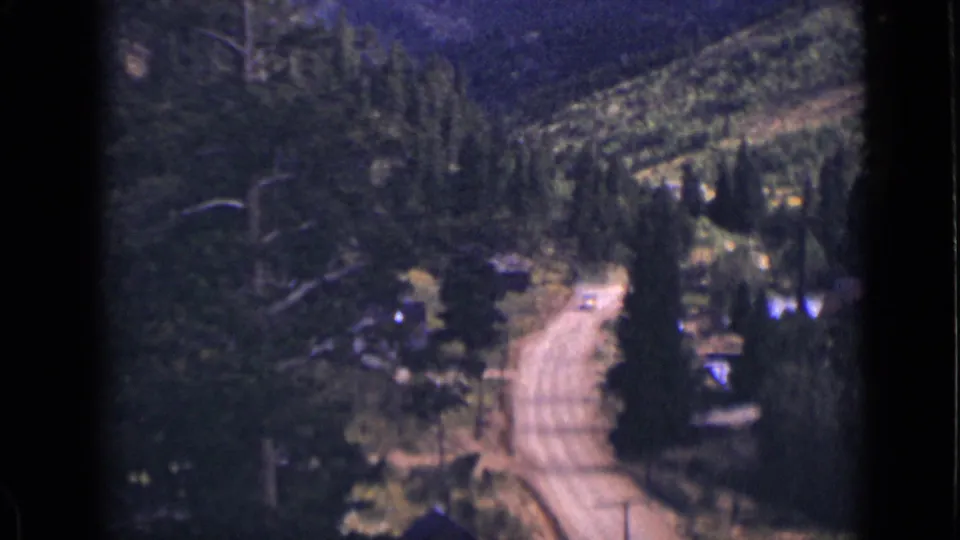 1939 Colorado frame showing a lone dirt road receding through forested mountain terrain.