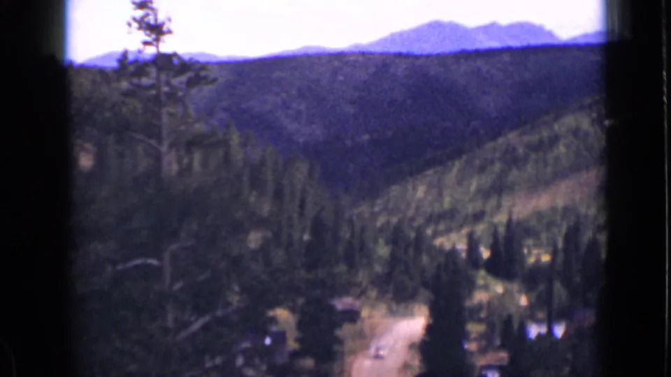 1939 Colorado 8mm frame with distant mountains, pine-covered hills, and a winding road in the lower valley.
