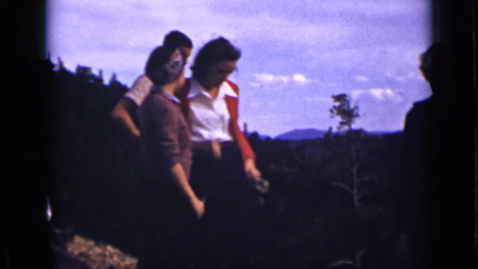 1939 Colorado home-movie frame of women gathered at a hilltop overlook, silhouetted partly against sky and mountain scenery.