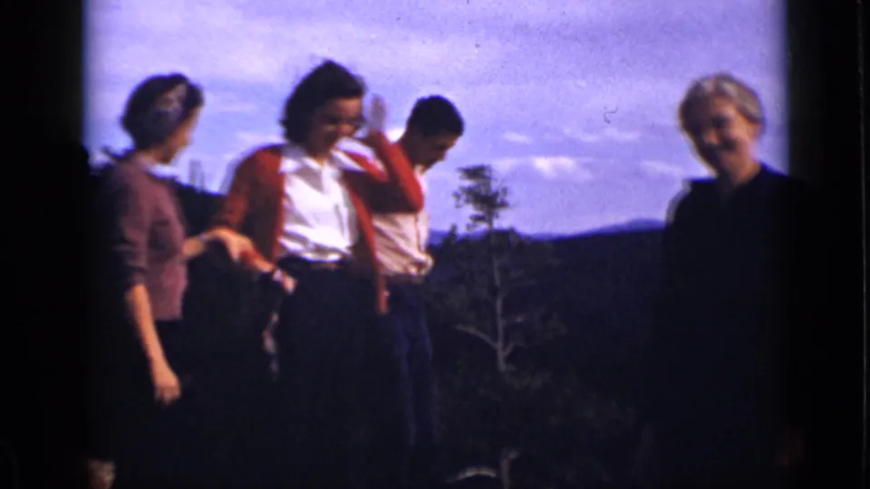 Four adults appear on a Colorado mountain overlook, shifting and smiling toward the camera in soft 8mm color footage.