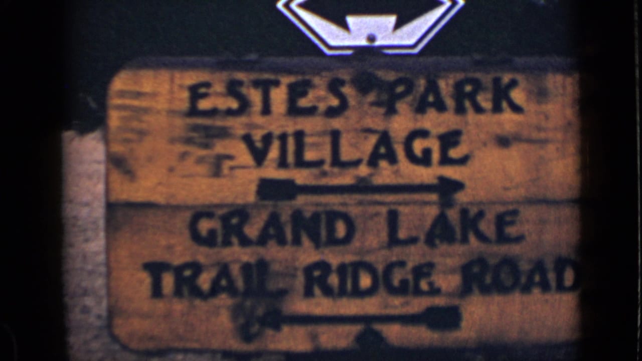 Wooden Colorado road sign with black lettering and arrows, seen in soft focus.