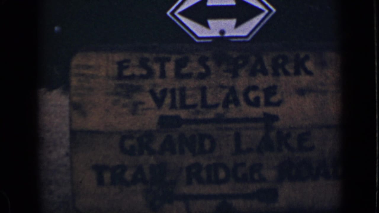 Weathered wooden sign pointing toward Estes Park Village and Grand Lake Trail Ridge Road.