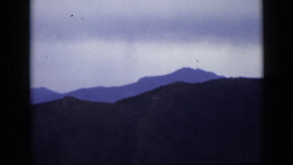 1939 Colorado 8mm frame showing dark mountain ridges layered against a pale, clouded sky.