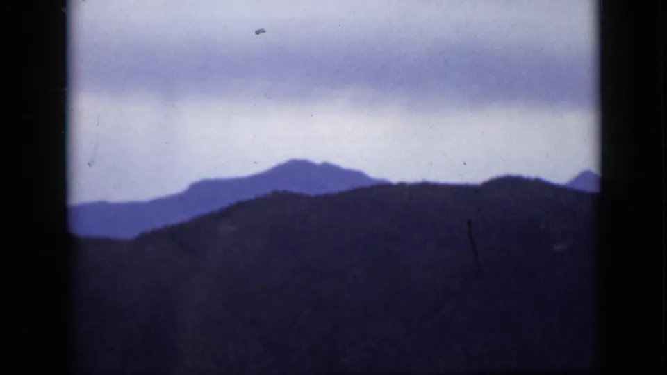 Colorado mountain silhouettes appear in soft blue tones beneath a cloudy sky in this 1939 8mm home-movie frame.