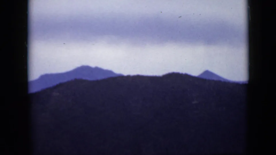 1939 Colorado 8mm view of low ridges and distant peaks silhouetted against a muted overcast sky.