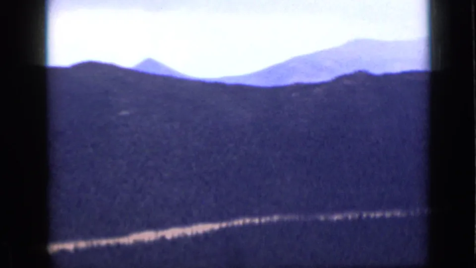 1939 Colorado 8mm frame of blue-toned mountain ridges and a light road or clearing running along the lower slope.