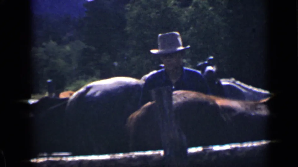 In Colorado 1939 home-movie footage, a hat-wearing man stands or rides beside a horse while another rider is visible behind.