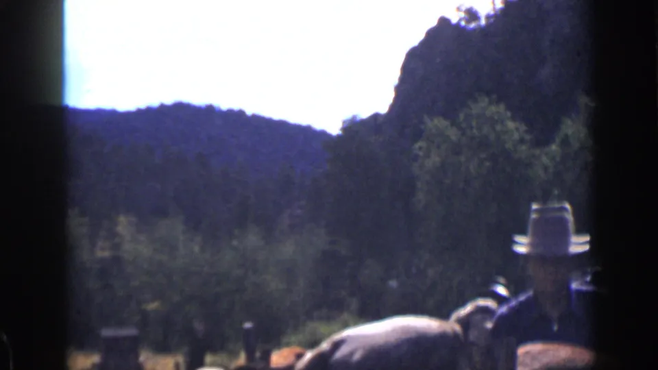 1939 Colorado 8mm frame with a partly visible man in a hat, horses, trees, and a dark hillside in the background.