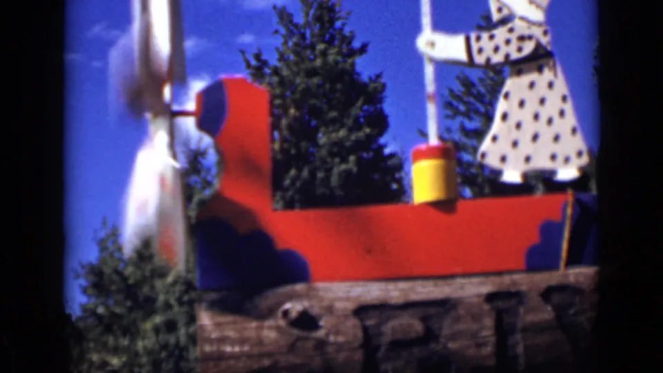 1939 Colorado 8mm frame of a red, white, and blue painted windmill with a polka-dot butter-churning figure outdoors.