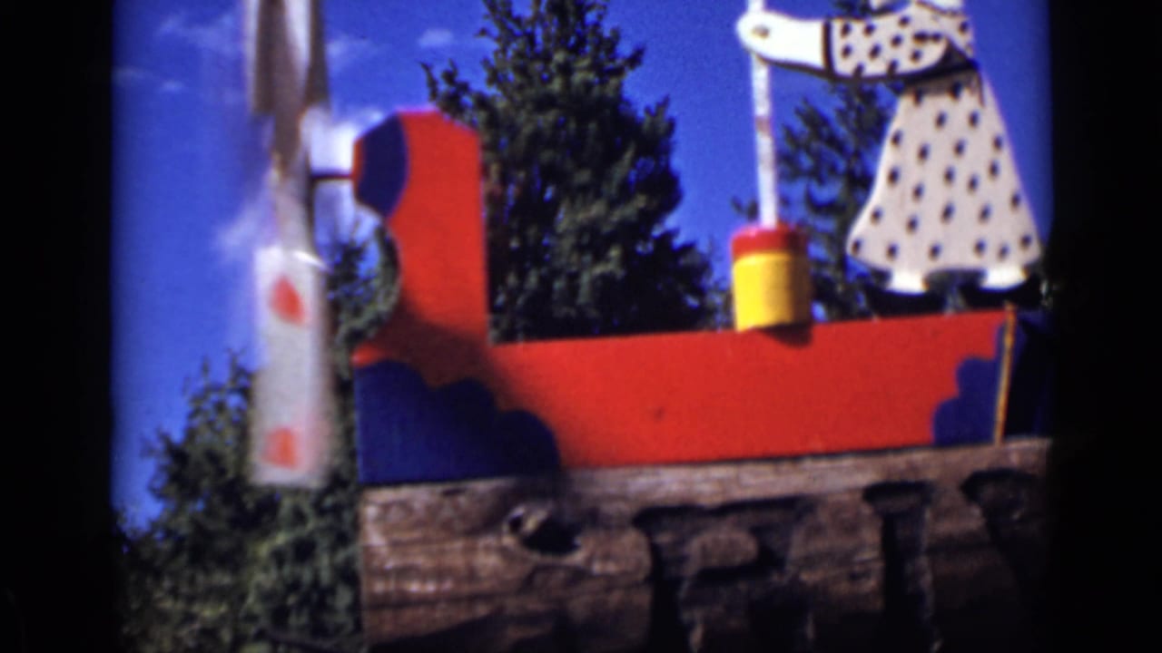 Colorful handmade wooden display with a polka-dotted figure and windmill form under blue sky.