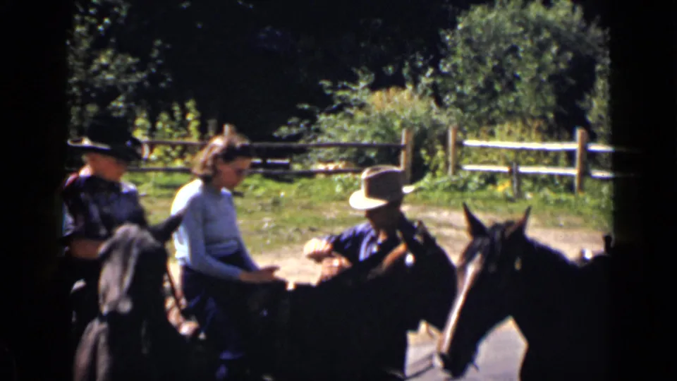 1939 Colorado ranch scene with multiple riders on horseback grouped near trees and a split-rail fence.
