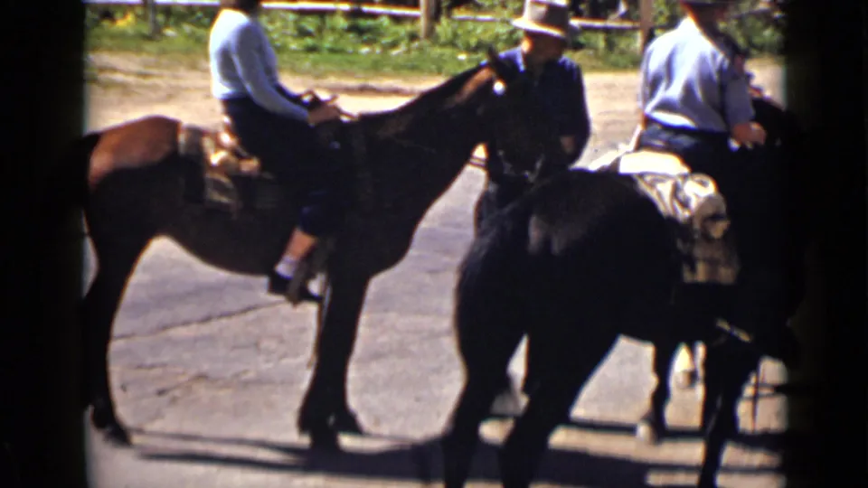 1939 Colorado frame of riders on saddled horses pausing on a paved path, with hats and outdoor fencing visible.
